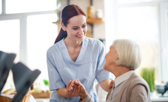 A nurse helps a senior woman at a memory care community